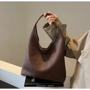Close-up of the intricate woven leather texture on a dark brown oversized tote bag