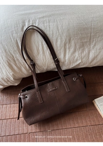 Close-up of retro dark brown leather tote bag with MUTING logo and metal details