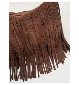 Primo piano borsa bohémien marrone scuro scamosciata con frange fitte e dettagli nappe