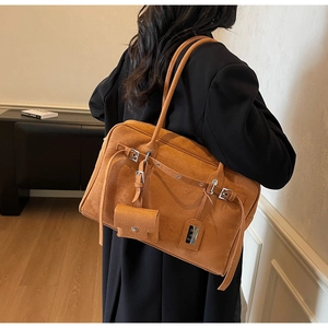 Detail of brown suede hobo bag with decorative belts, metal buckles and mini pouch charm