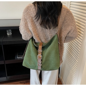 Detail of dark green tote bag with brown leather straps and silver metal buckles