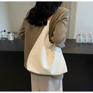 Detail of white woven tote bag showing texture and brown leather straps on shoulder