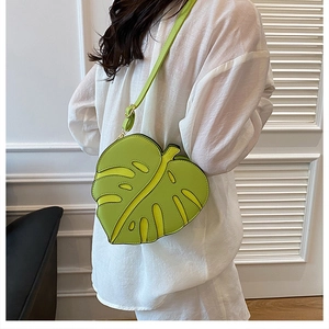 Detail of leaf-shaped green crossbody bag with yellow accents and adjustable shoulder strap