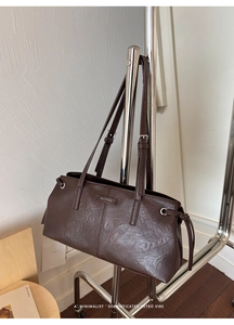 Detail of dark brown tote bag featuring premium lychee texture and metallic logo