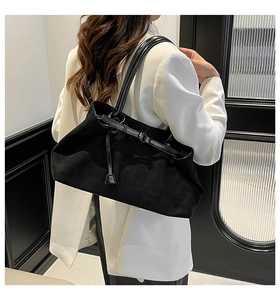 Dettaglio di una grande borsa tote in pelle scamosciata nera su modella in abito bianco