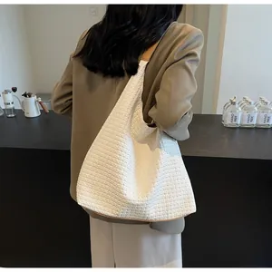 Detail of white woven tote bag with soft texture and brown leather shoulder strap