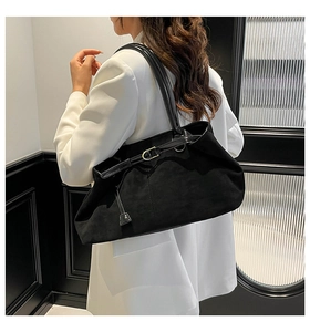Detalle de bolso tote de ante negro con correa de cuero y herrajes dorados elegantes