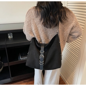 Detail of black matte suede tote bag featuring a decorative metal buckle strap design