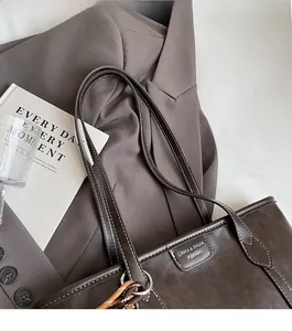 Detail of dark brown leather tote with white stitching and vintage leather logo tag