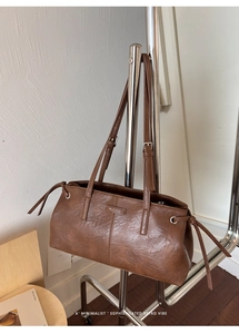 Close-up of the vintage brown leather shoulder bag featuring a Muting brand logo and drawstring
