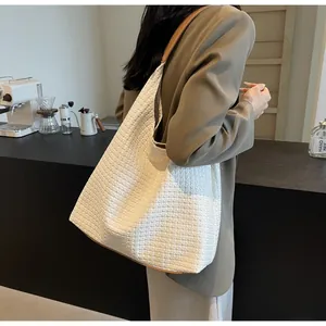 Detailed view of woven tote bag with white diamond patterns and brown leather edges