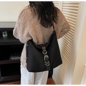 Detail of black large hobo bag with leather strap and silver buckle on female model