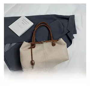 Detailed top view of large straw tote bag with brown leather straps on a grey suit jacket