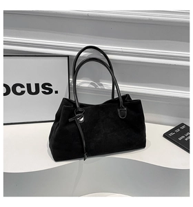 Dettaglio borsa tote in pelle scamosciata nera con manici in pelle e cinturino decorativo