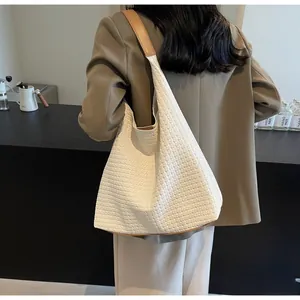 Rear view of model wearing a white woven tote bag with brown leather shoulder straps