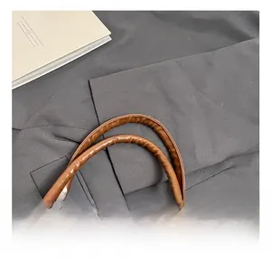 Detailed close-up of thick brown textured leather handle on a large commuter tote bag
