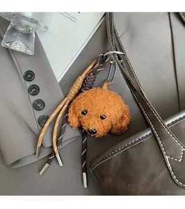 Brown curly plush poodle charm with braided rope on a stylish leather tote bag