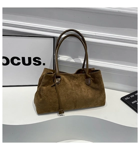 Dettaglio della borsa tote in pelle scamosciata marrone con cuciture e manico in pelle