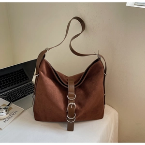 Detail of a large brown suede tote bag with metal ring buckles and adjustable strap