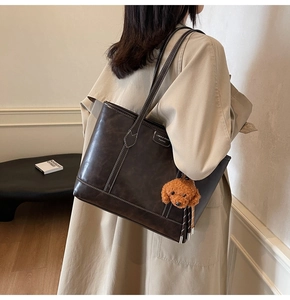 Detail of vintage brown tote bag with contrast stitching and teddy plush pendant