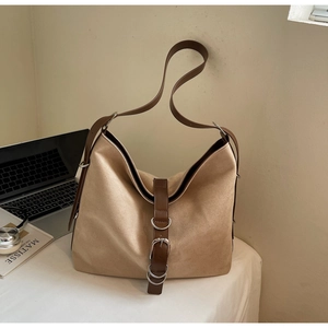 Detail of khaki suede tote bag with brown leather straps and silver metal buckles