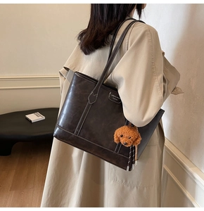 Detail of vintage coffee leather tote bag with white stitching and puppy charm