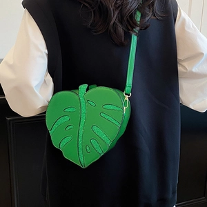 Unique green monstera leaf shaped crossbody bag with glitter veins worn by a model