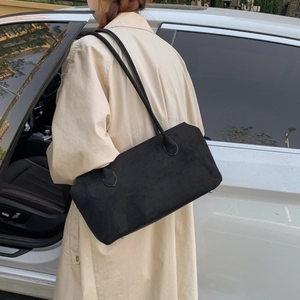 Minimalistische schwarze Wildleder-Tasche getragen mit einem schicken Herbst-Trenchcoat