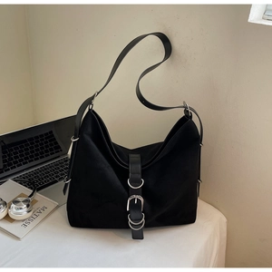 Detail of a large black tote bag with silver metal rings and buckles on a desk
