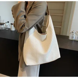 Detail of the white woven texture and brown leather trim on a large tote shoulder bag
