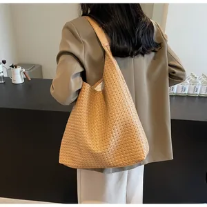 Close-up of woven tote bag texture and integrated strap worn by model in a blazer