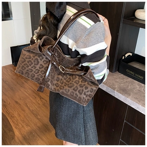 Detail of leopard print tote bag featuring brown leather straps and gold metal buckle