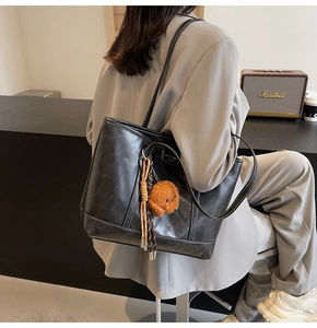 Detailed back view of a black leather tote bag with white stitching and puppy charm