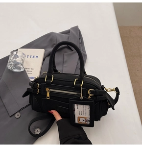 Detail of black bowling bag with gold hardware and stylish cartoon decorative tag