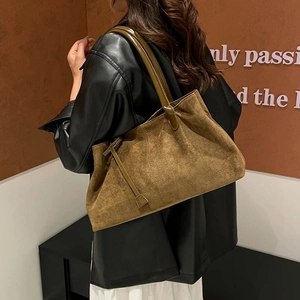 Bolso tote marrón de ante con correas de cuero visto desde el lateral en una modelo