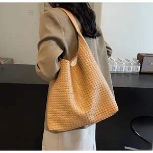 Close-up of the large woven leather tote bag texture and durable shoulder strap design