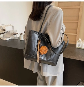 Detailed view of a black tote bag with white contrast stitching and a cute dog charm