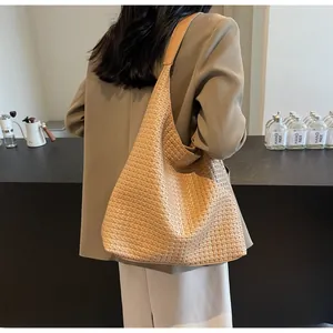 Detail of a large woven hobo bag in khaki faux leather worn over the shoulder