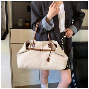 Detail of canvas tote bag with brown leather handles and side strap accent on a model