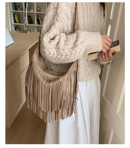 Dettaglio di borsa hobo beige con frange abbinata a un maglione in maglia