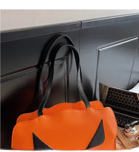 Detailansicht der orangefarbenen Kürbis-Tasche mit schwarzer Textur und Ledergriffen