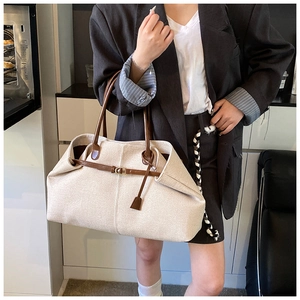 Woman carrying large cream canvas and brown leather tote bag for casual commuting