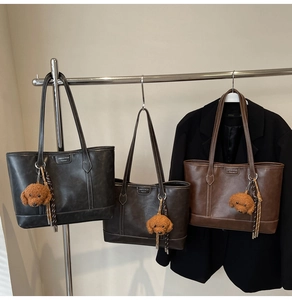 Retro tote bags in black, coffee and brown with plush puppy charms on a display rack
