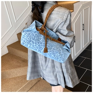 Detailed back view of a blue leopard print tote bag with brown leather shoulder straps