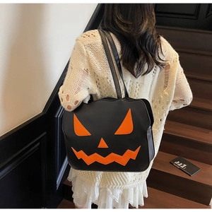 Detail of black leather pumpkin tote bag featuring vibrant orange jack-o'-lantern face