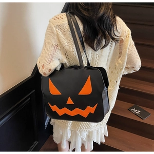Detail of black leather Halloween pumpkin tote bag featuring orange face on shoulder strap