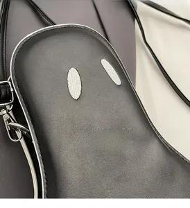 Close-up of black textured leather ghost bag with white oval patches and silver buckles