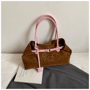 Detail of leopard print tote bag featuring pink handles and gold metal buckle hardware