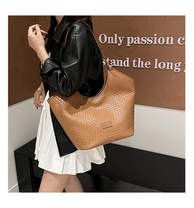 Grote bruine geweven shopper met een minimalistisch design gedragen door een model