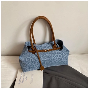 Detail of blue leopard print tote bag featuring brown faux suede texture and buckle